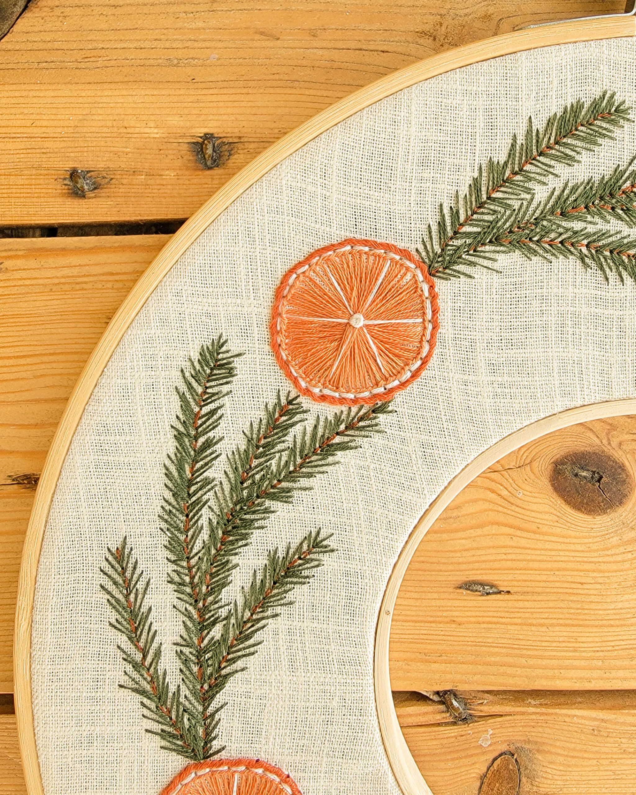 Broderie Noël représentant une couronne de sapin et d'oranges séchées
